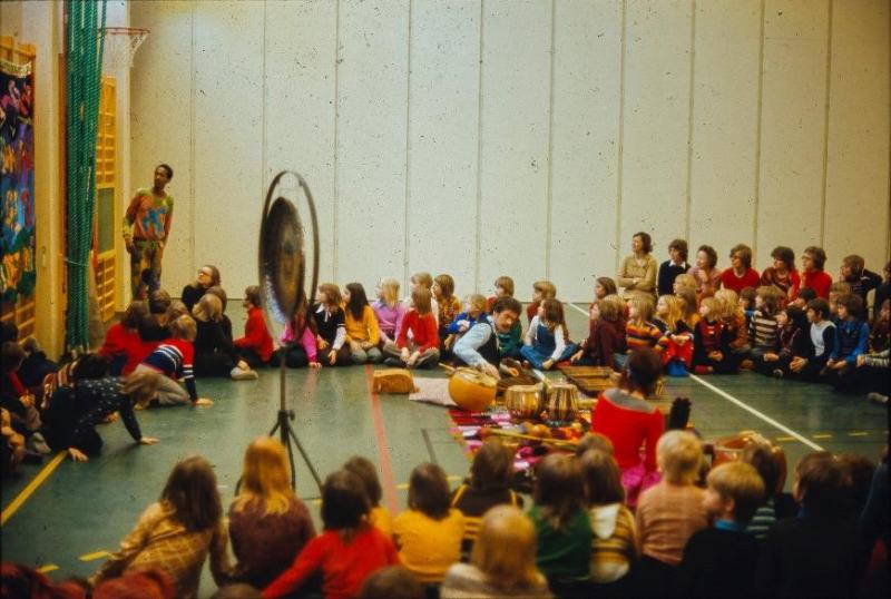 Photo of Don Cherry standing by Maulkans Raga tapestry by Moki at a children’s music workshop at a school in Sweden, c.1973, courtesy of the Cherry Archive, the Estate of Moki Cherry